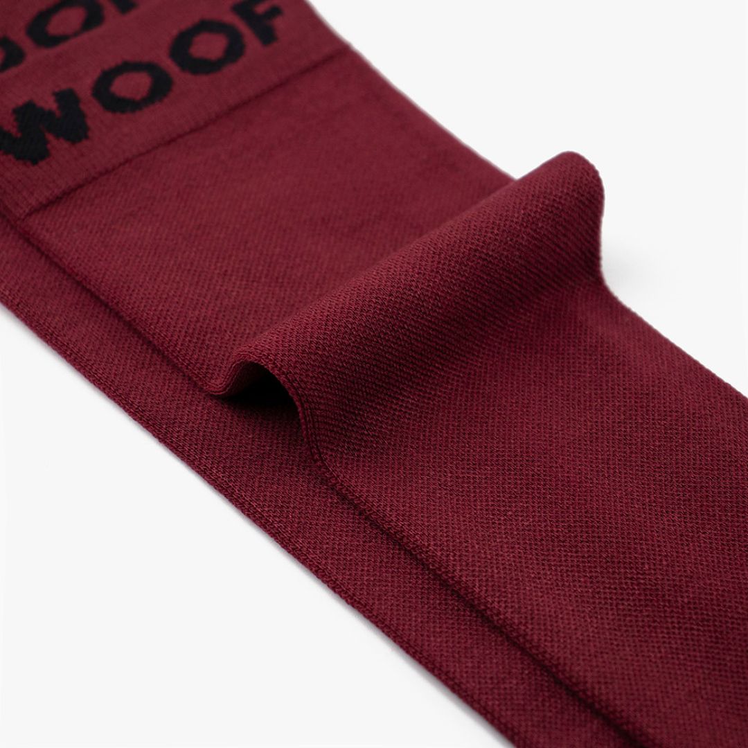 Folded view of solid maroon knee-high compression socks displaying top cuff branding.